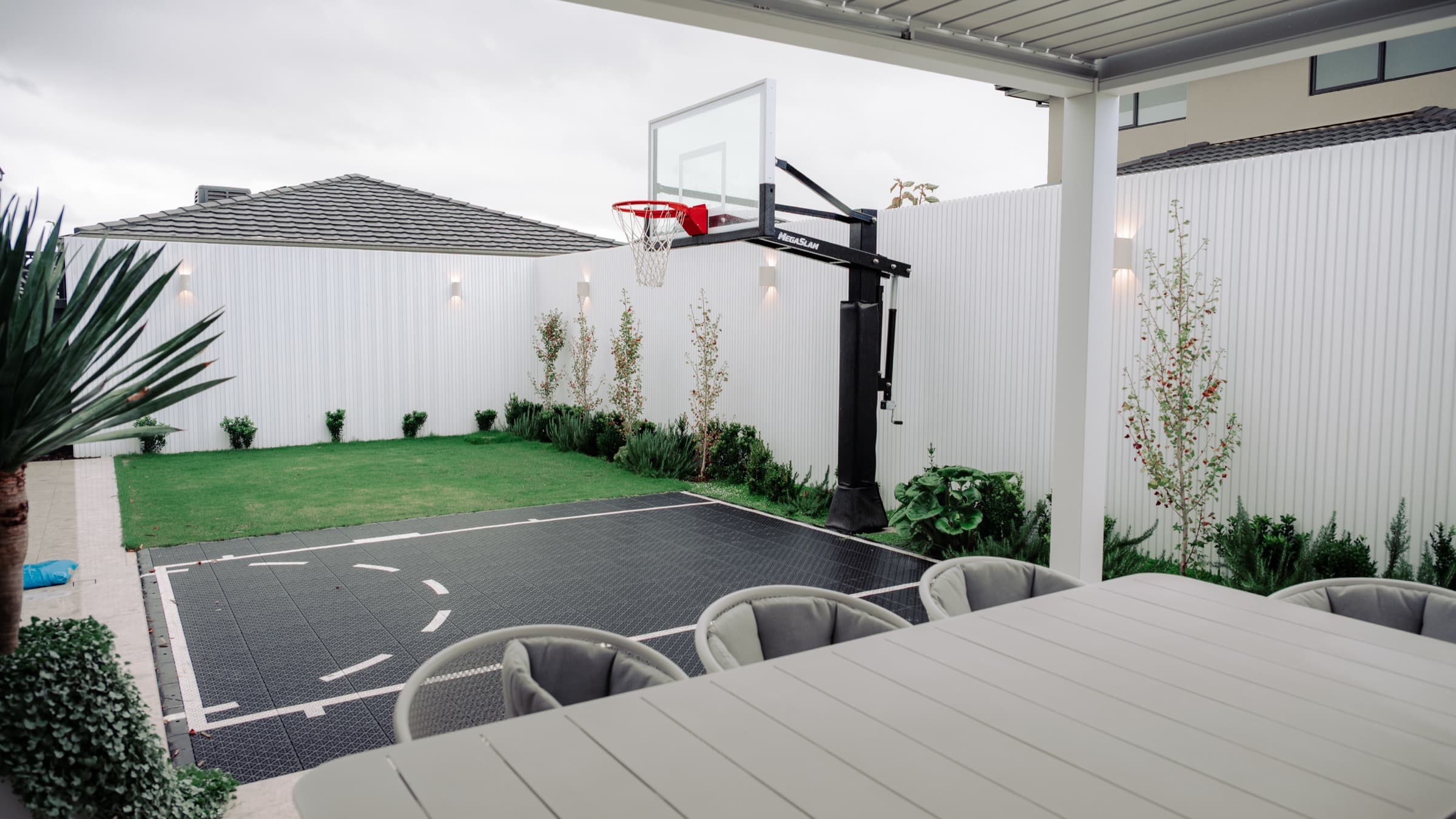 Covered dining area, basketball court, lawn and planting in a completed Clyde North backyard